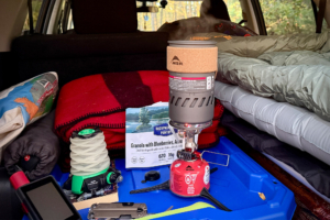 The MSR Switch boils water inside a car setup with blankets and gear packed for camping